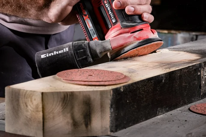 Person schleift Holz mit einem Schwingschleifer